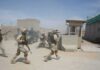 U.S. Forces Intercept Iranian Missile Attack Soldiers in desert uniforms run past a checkpoint amid dust