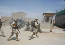 U.S. Forces Intercept Iranian Missile Attack Soldiers in desert uniforms run past a checkpoint amid dust