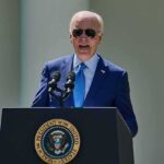 man in blue suit speaking at a podium with presidential seal