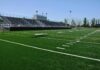 Empty football stadium with bleachers and artificial turf field