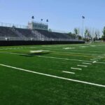 Empty football stadium with bleachers and artificial turf field