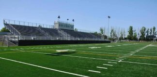 Empty football stadium with bleachers and artificial turf field