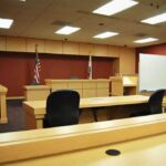 Interior view of an empty courtroom with wooden furniture and American flags
