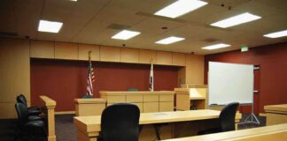 Interior view of an empty courtroom with wooden furniture and American flags
