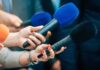 Red Paint Fury Hits TPUSA Memorial Reporters holding colorful microphones