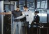 airport security officer wands traveler at metal detector