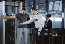 airport security officer wands traveler at metal detector