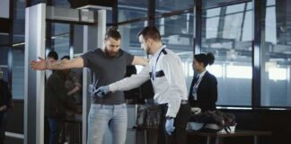 airport security officer wands traveler at metal detector