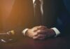 London Tourist Reports Phone Grab Attempt person in suit with hands clasped at a desk beside a gavel