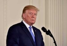 Trump Video Portrays Him as “God’s Caretaker” man in suit at a podium