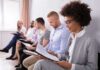 Group of job applicants sitting in a row reviewing documents