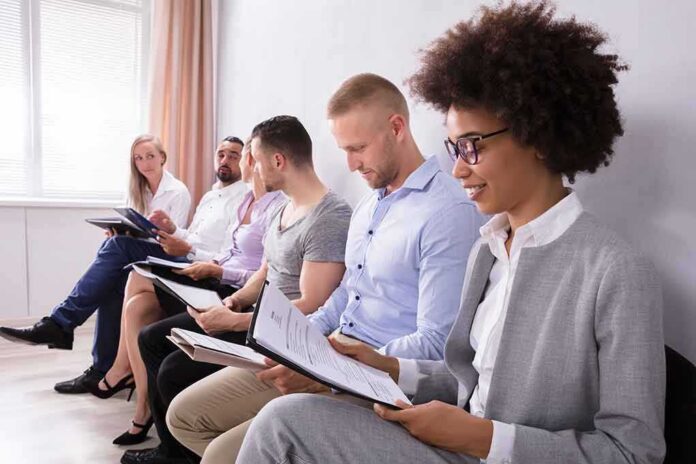 Group of job applicants sitting in a row reviewing documents