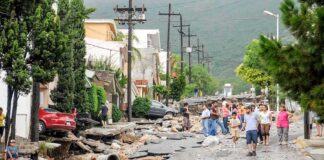 Residents walk along a heavily damaged street after a disaster