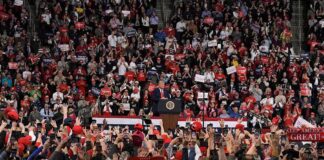 Speaker at podium addressing large crowd in arena
