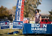 Volunteer at outdoor campaign table with Biden Harris signs