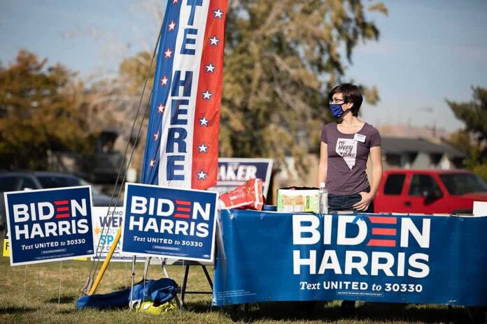 Volunteer at outdoor campaign table with Biden Harris signs