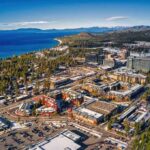 Aerial view of lakeside city with casinos, hotels, and pine forests