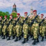 Soldiers in camouflage uniforms march in formation with rifles