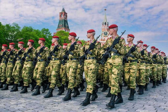 Soldiers in camouflage uniforms march in formation with rifles