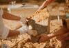 Archaeologists cleaning a large stone artifact at a dig site