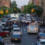 Police vehicles and officers block a city street during an active scene