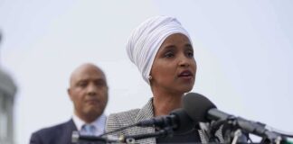 Ilhan Omar speaking at a podium with André Carson standing behind