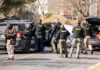Manhunt Chaos: Helicopter Hit, Town Locked Down Police and sheriff officers gather around vehicles on a suburban street