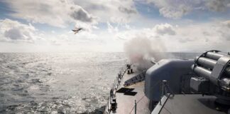 naval warship firing deck gun at sea