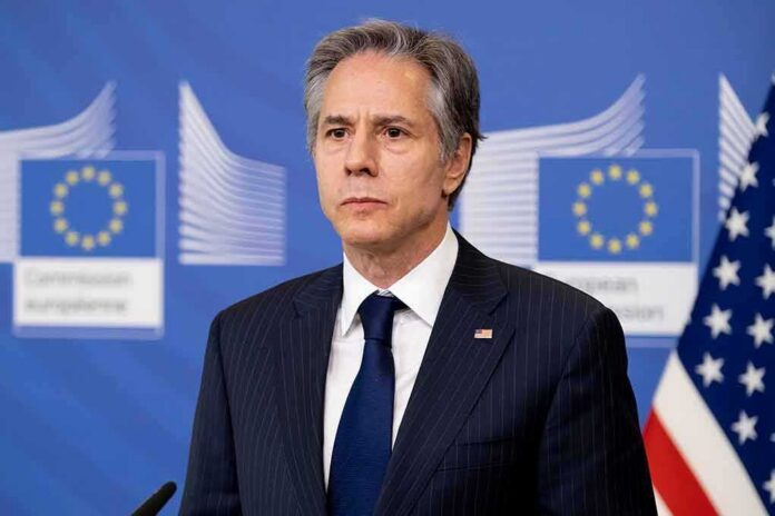 shutterstock_2132453655 Man in suit at press conference with EU and US flags behind