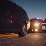 Police officer at patrol car during traffic stop at dusk