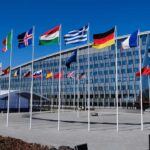 EU Approves Toughest Migrant Deportation Crackdown in Decades Row of national flags outside a modern glass office building