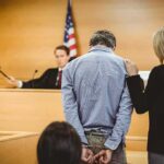 Courtroom Confession Shocks Federal Case Defendant in handcuffs stands before a judge in a courtroom