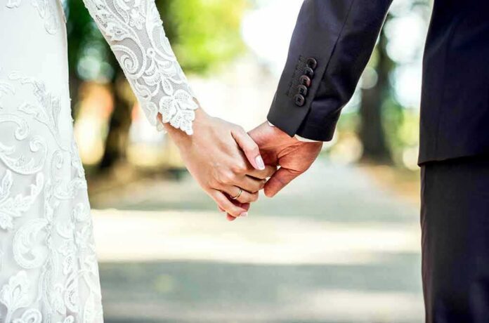 shutterstock_340594079 Bride and groom holding hands outdoors