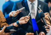 Apple Enters a New Era Man in suit surrounded by microphones at press conference