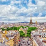 Eiffel Tower over Paris skyline with French flag in foreground