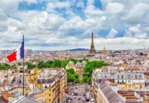 Eiffel Tower over Paris skyline with French flag in foreground