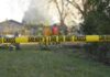 Woman Falls Into 8-Foot Backyard Hole Yellow police tape marking a restricted area at a fire scene with firefighters in the background