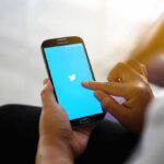 Person using smartphone with blue bird app screen