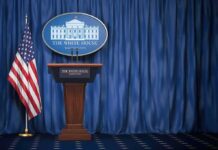 North Korea Diplomacy May Be Back on the Table White House press briefing podium with U.S. flag and blue curtain