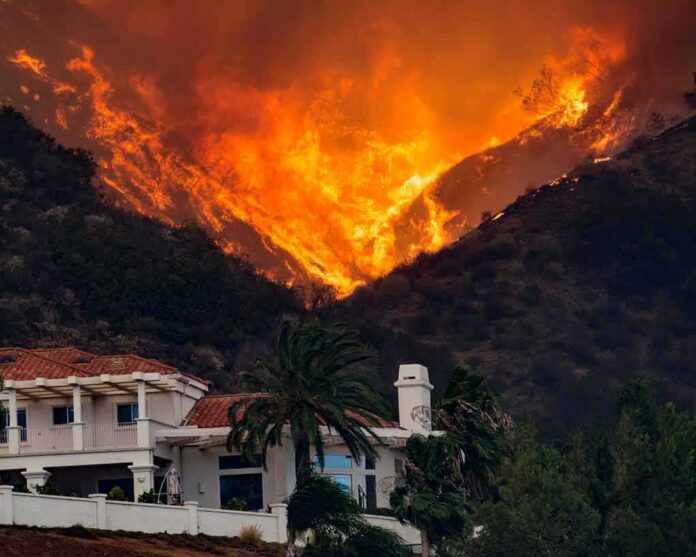 shutterstock_1281996298 Wildfire engulfs hillside behind a suburban house