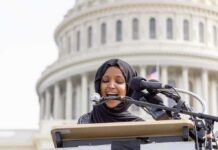FBI Hub: New Plan Targets Online Gang Threats Woman in hijab speaking at podium with microphones