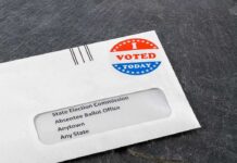 Trump Raises Election Fraud Fears Absentee ballot envelope with I Voted sticker on dark surface