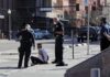 Australian MP Critically Injured in Car Strike Police officers detain a seated man on a city sidewalk