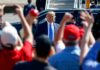 Trump Blends Rally Politics With Policy Claims Man in suit greeted by crowd with raised hands
