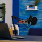 Execution Broadcast Sparks Debate Podcast microphone and laptop on desk in modern studio