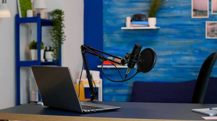 shutterstock_1939096570 Podcast microphone and laptop on desk in modern studio