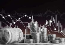 Stacks of coins and rolled dollar bills with falling financial charts