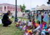 “Traitor” Chants Follow Mamdani at Vigil Police officer kneels at a memorial with flowers and crosses