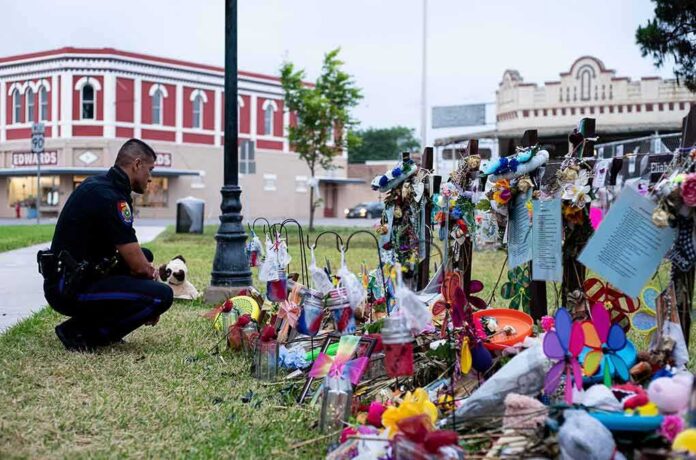 shutterstock_2167349635 Police officer kneels at a memorial with flowers and crosses