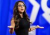 Defamation Suit Raises Questions Over $100K Claim Woman speaking on stage with arms outstretched